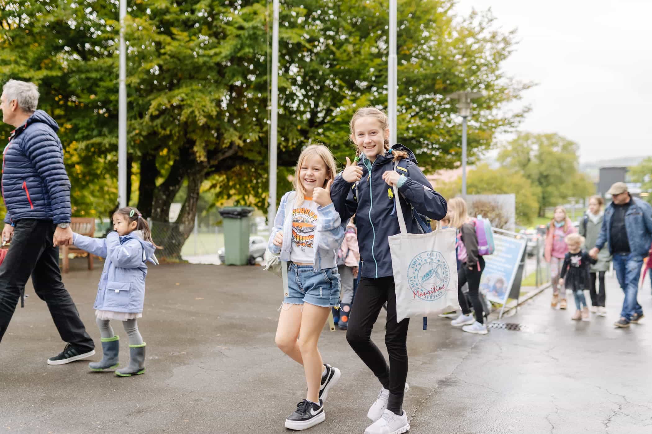 Two students smiling as they walk toward the school entrance, reflecting ISZL’s welcoming community and positive learning environment.