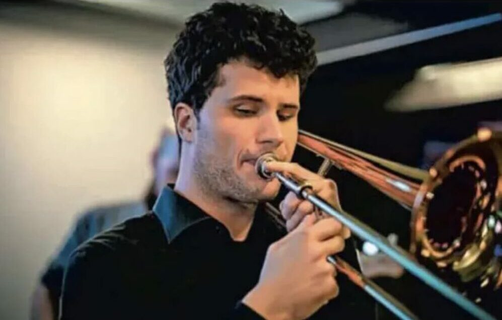 ISZL alumnus playing the trumpet on stage, showcasing the musical talent nurtured by the school.