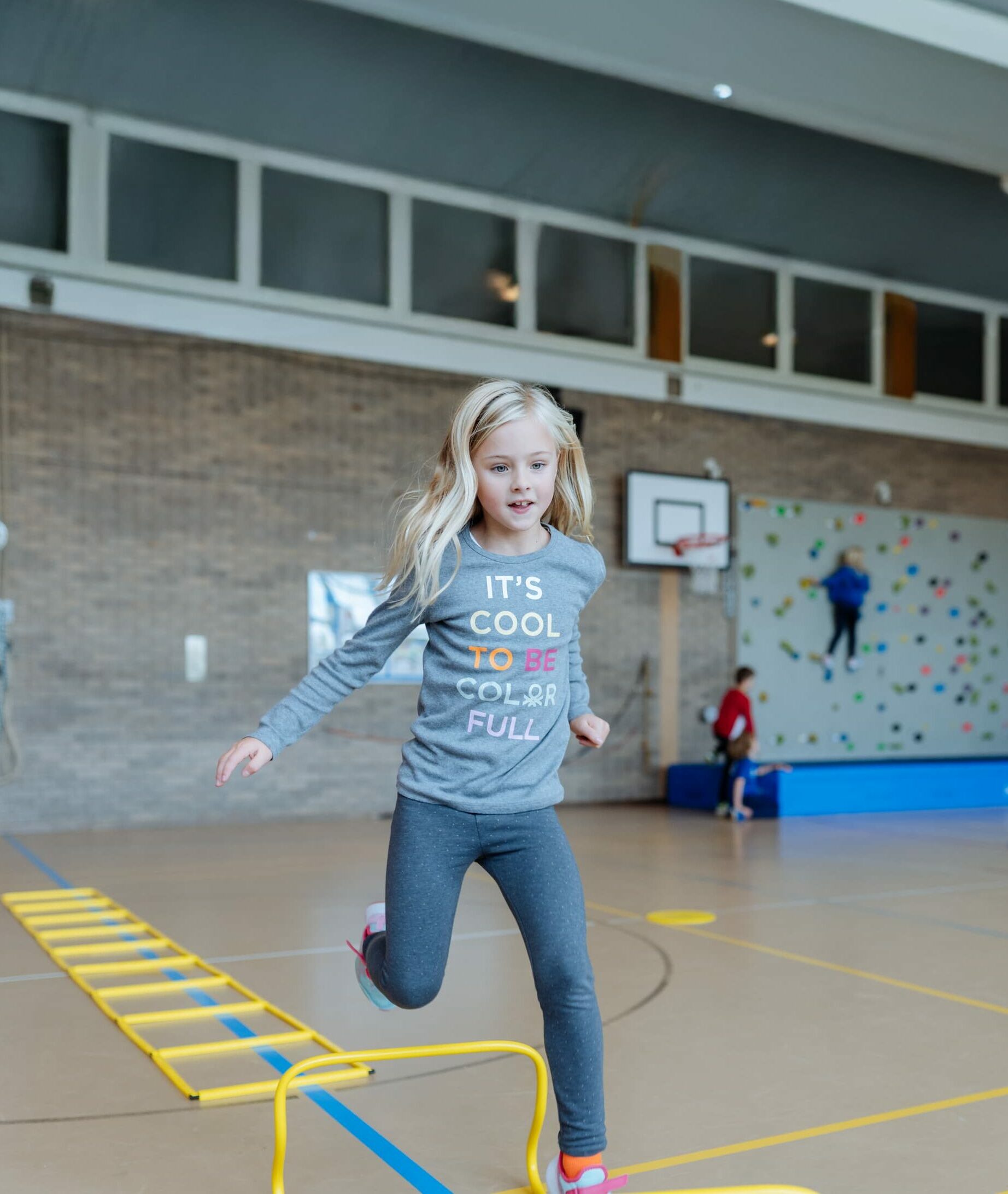 Primary School student jumping in an indoor gym during a sports activity.