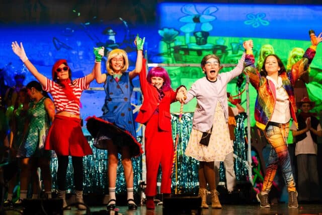Middle School student bowing on stage after a school musical performance.