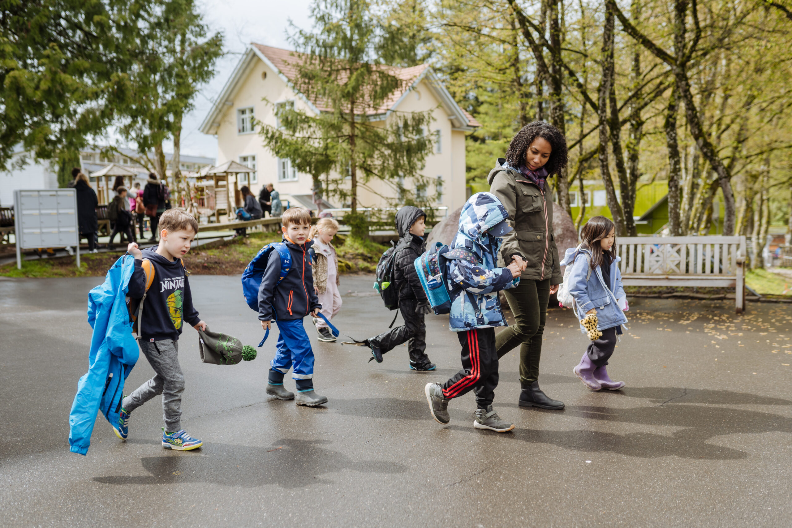 Primary school students leaving the school building, accompanied by a teacher.