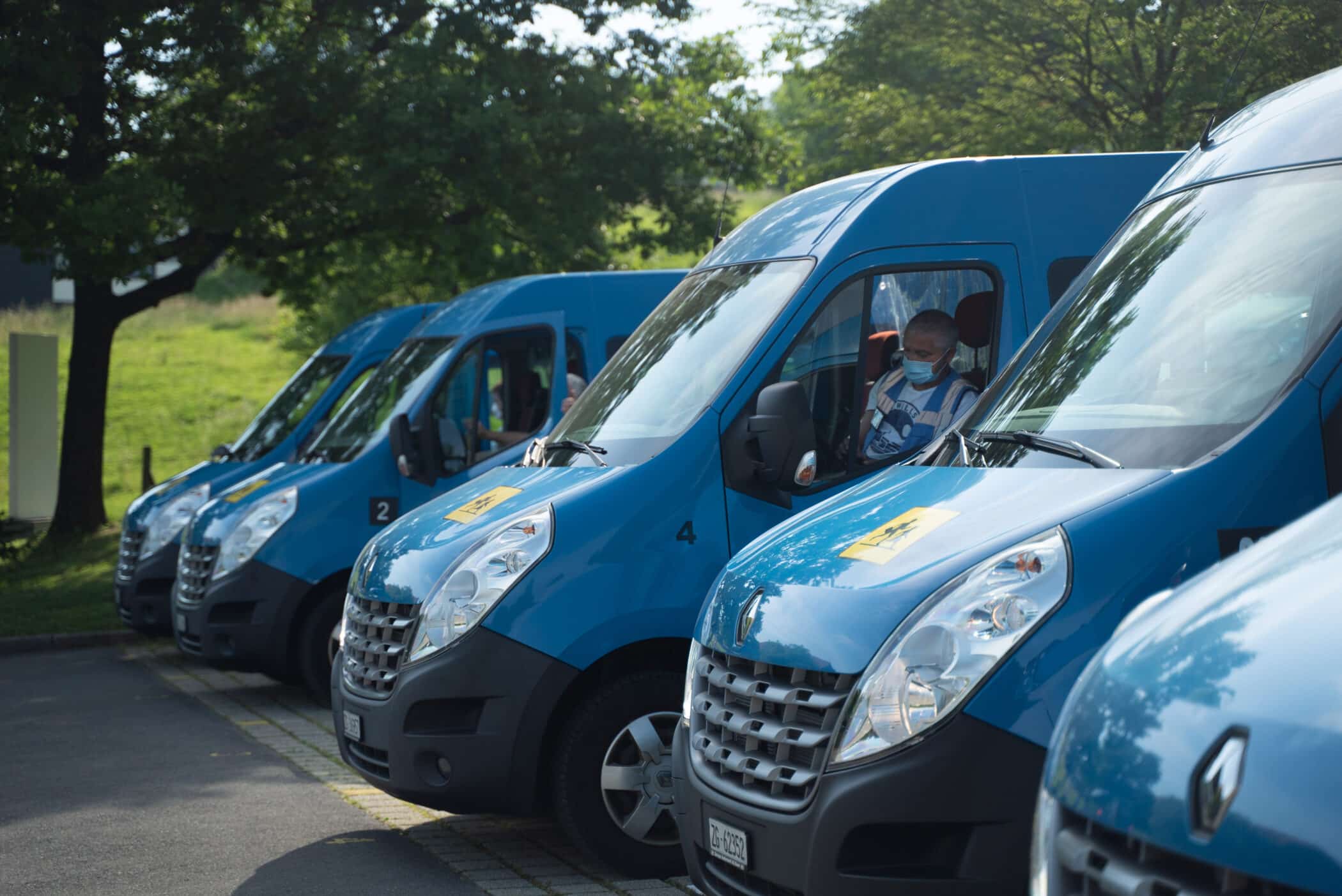 Fleet of blue ISZL school buses parked, ready to transport students safely to and from the Zug Campus.