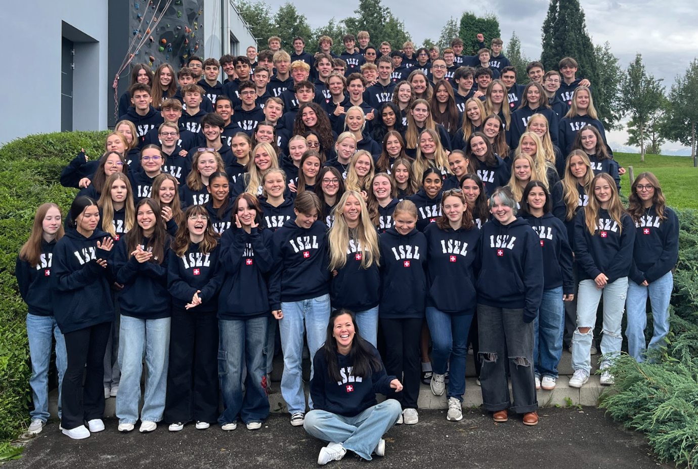 class 2025 High School students gathered together outside the school building, smiling and enjoying the campus environment.