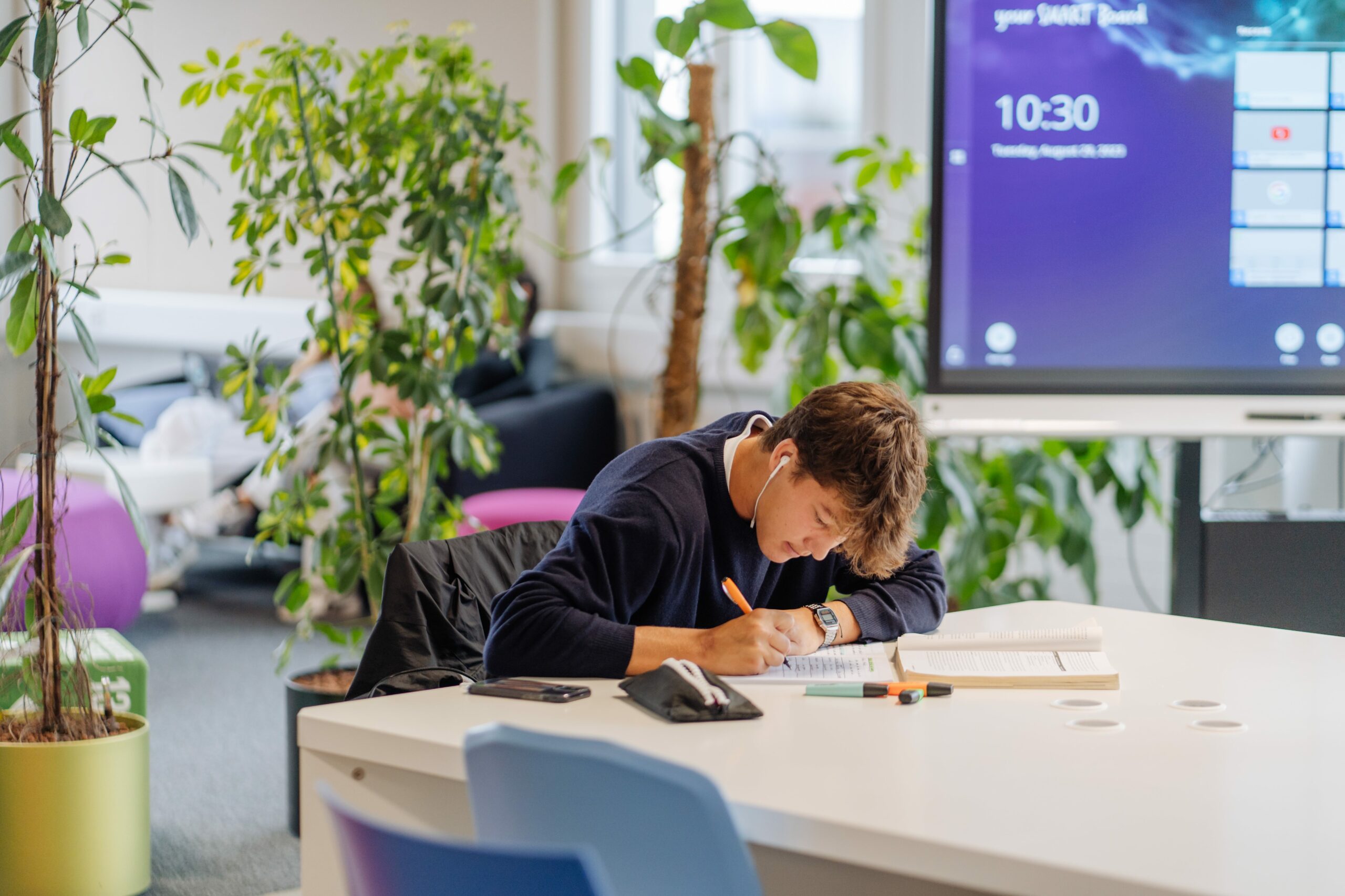 Student studying in a bright, modern High School space with plants and advanced technology at ISZL.