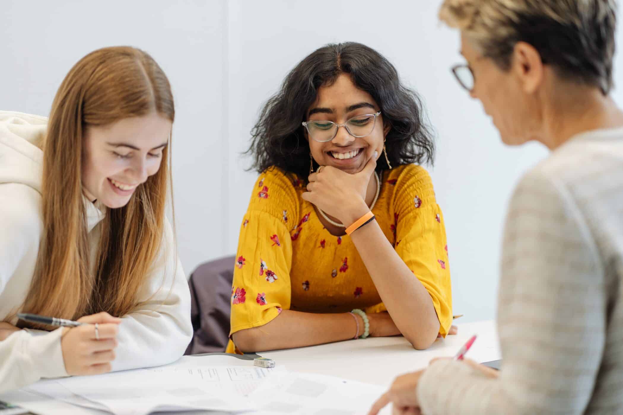 Two female students and an teacher engaged in a meeting during a school day.