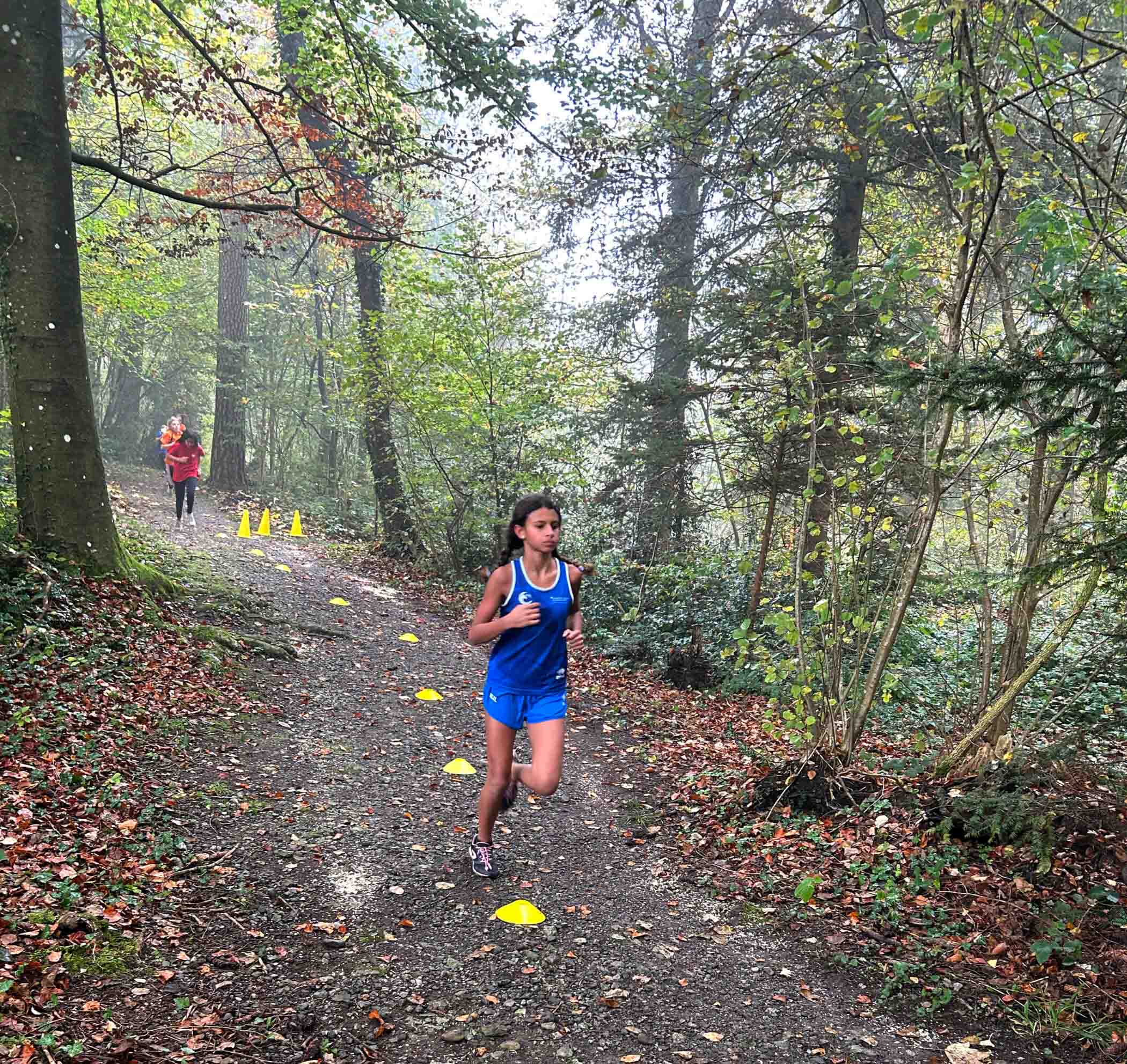 Female ISZL primary school student running through a Swiss forest during cross-country practice