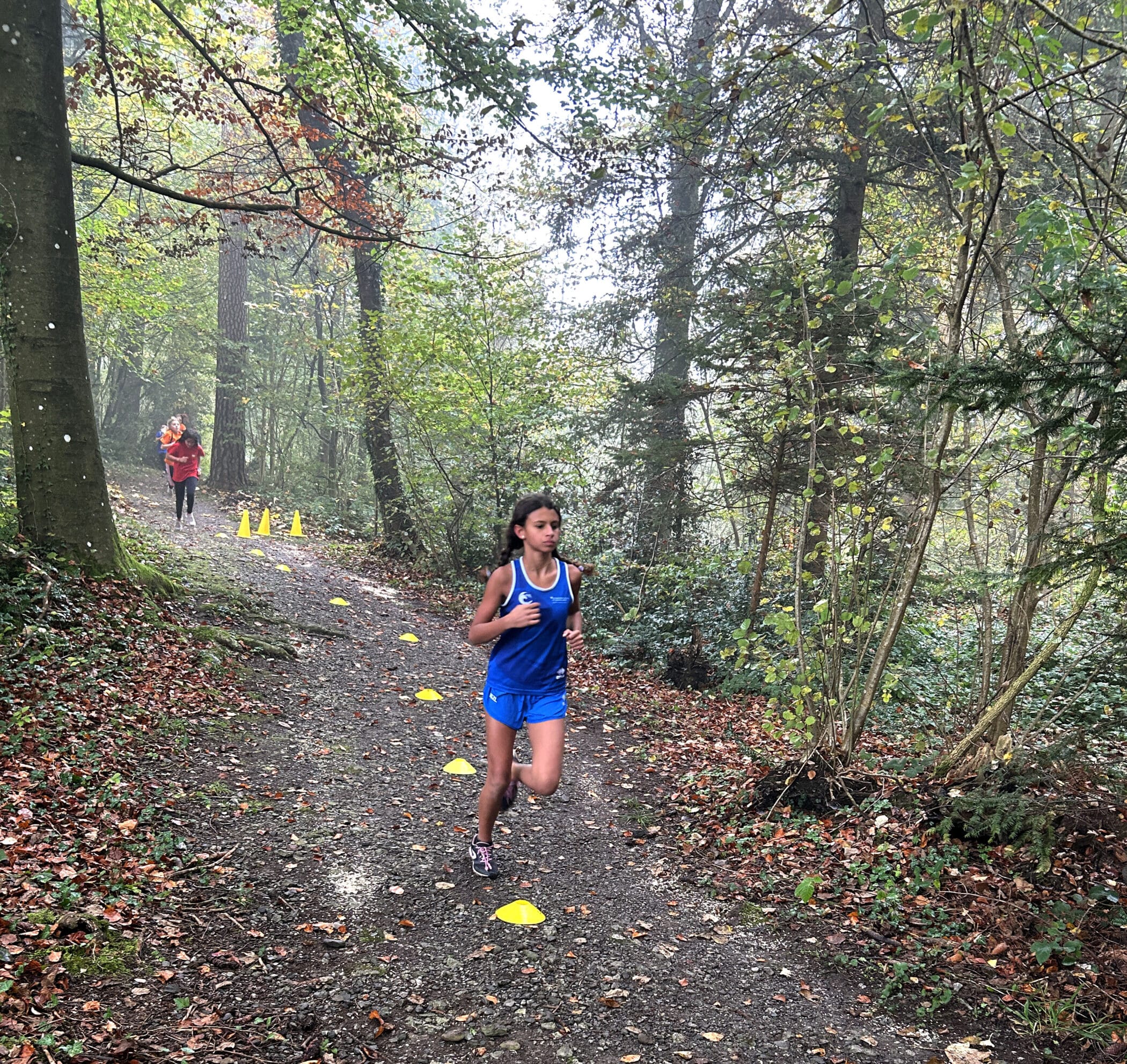 Female ISZL primary school student running through a Swiss forest during cross-country practice