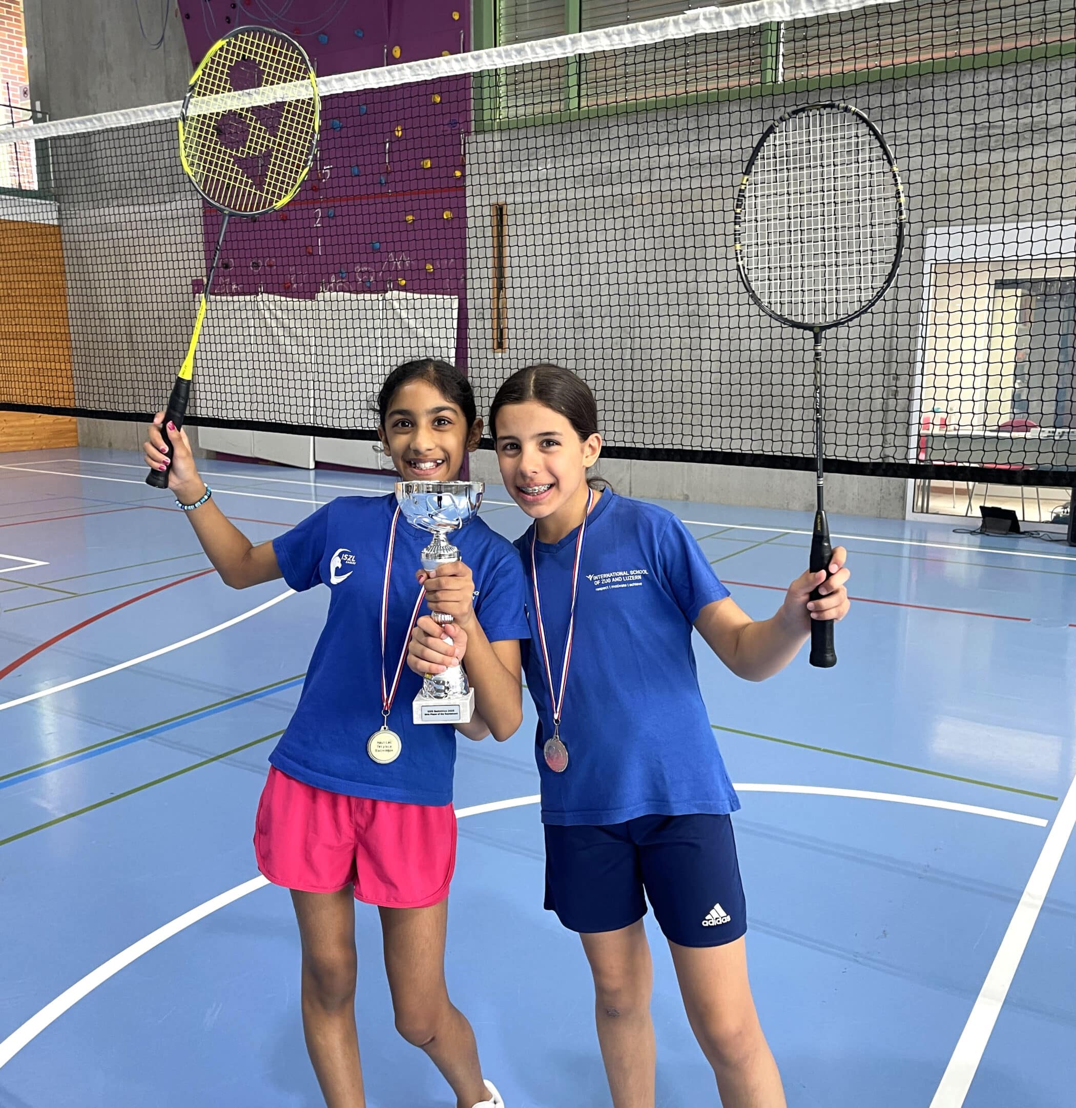 Two ISZL primary school students holding a trophy after a badminton match