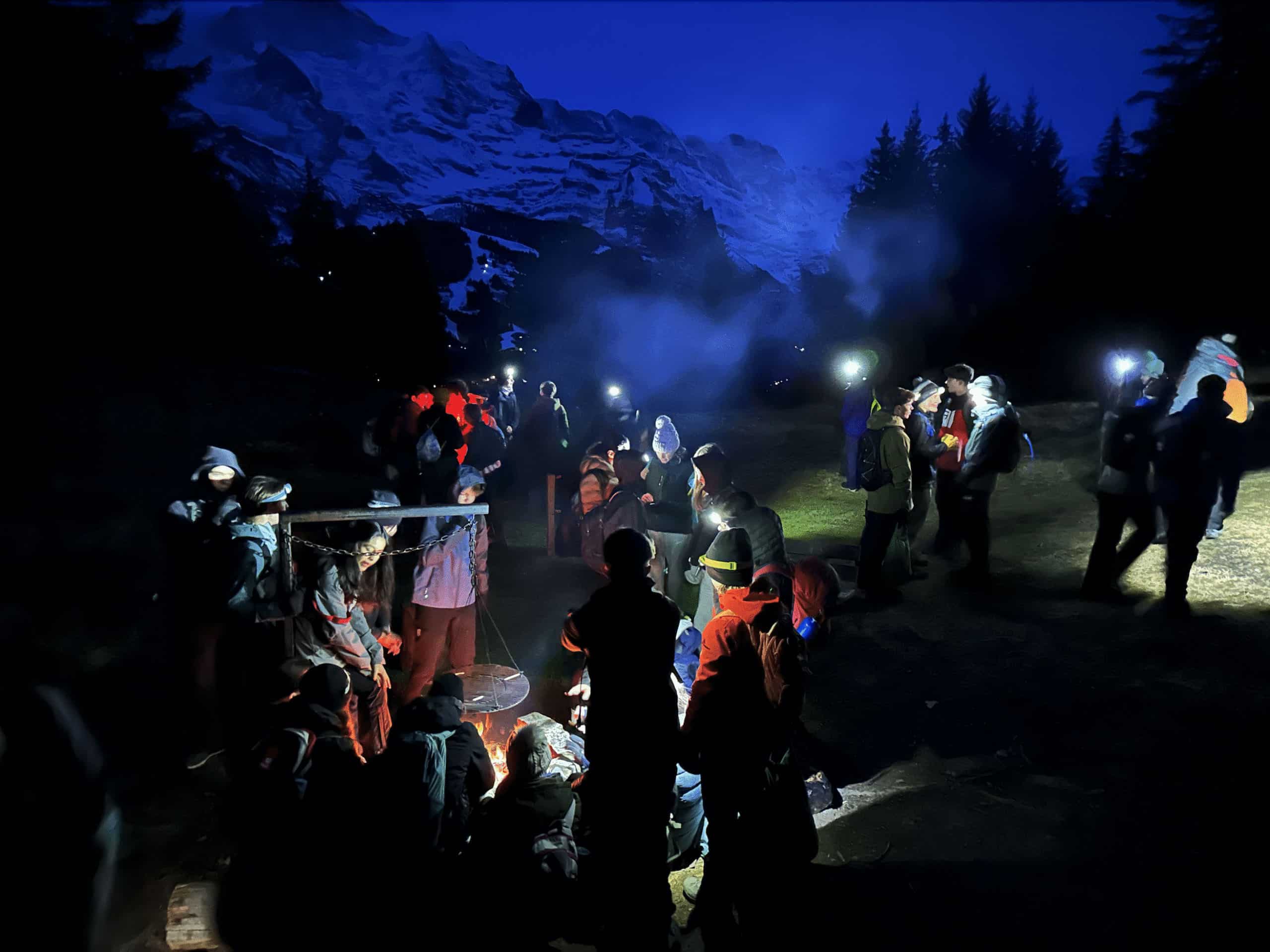 students with torches at night in the mountains