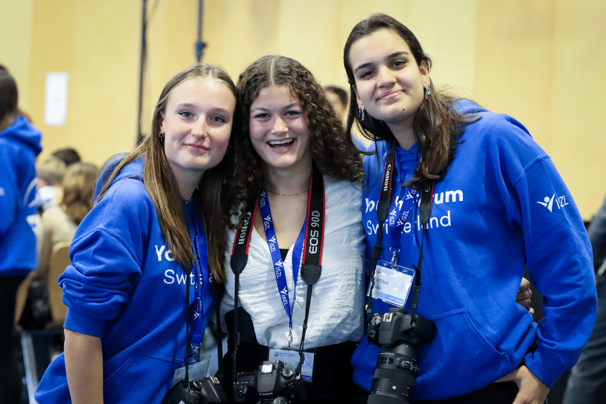 Three students smiling and enjoying themselves together at the Youth Forum Switzerland event.