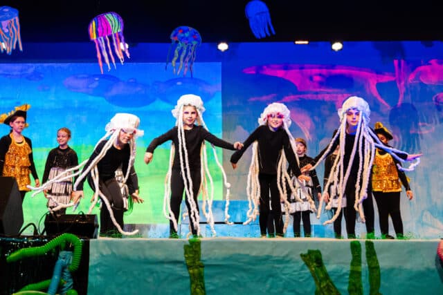 Children performing on stage during a primary school musical event at ISZL, celebrating creativity and community spirit.