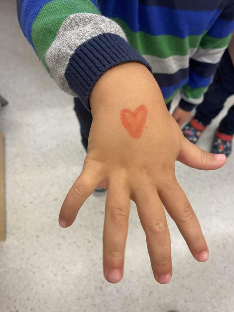 Child with a heart drawn on the back of their hand.