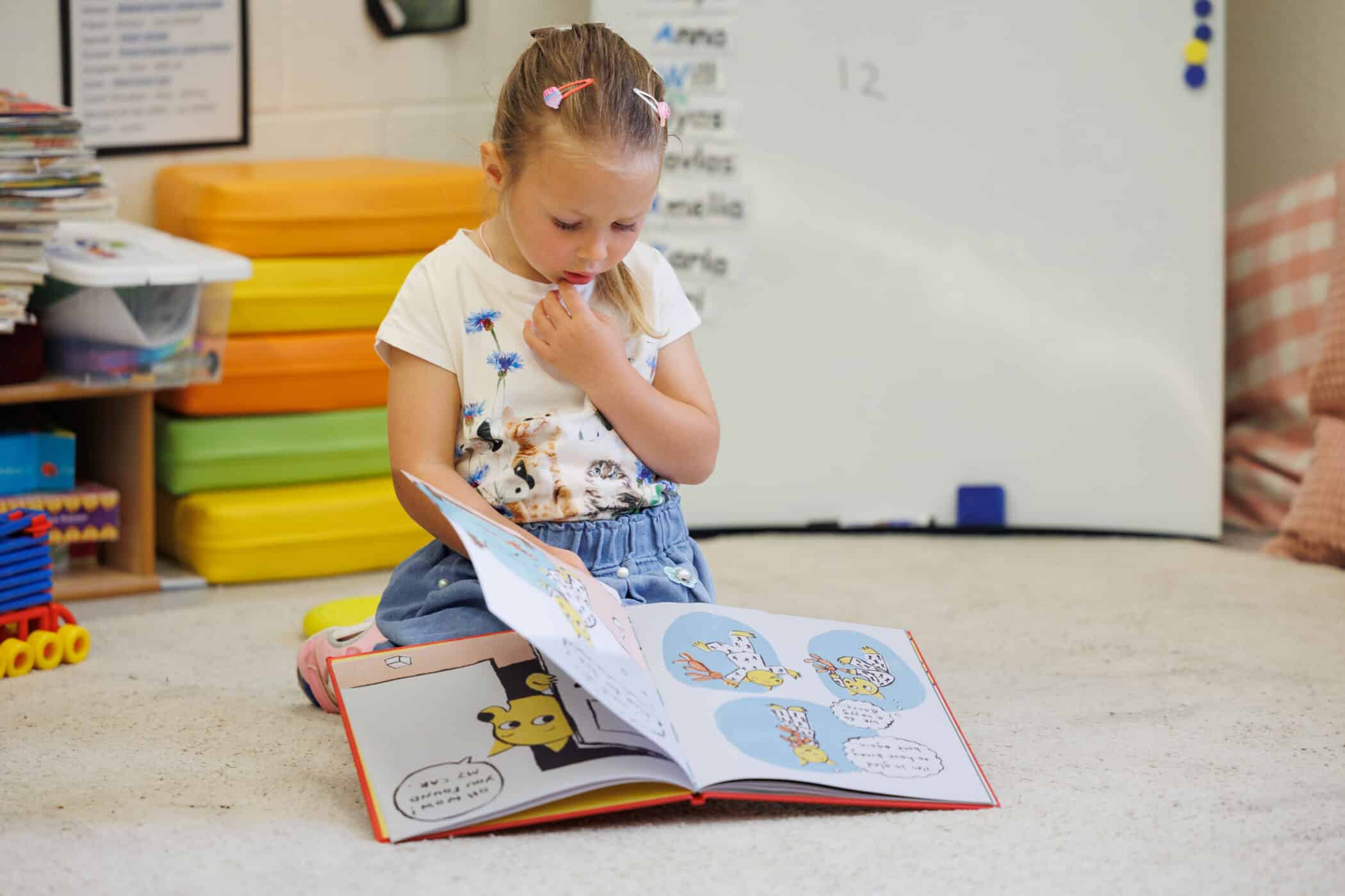 young student reading a picture book in the library