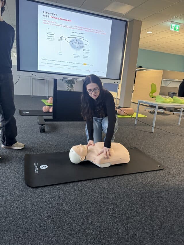 Students practise primary assessment techniques during a hands-on first aid certification session using training equipment.