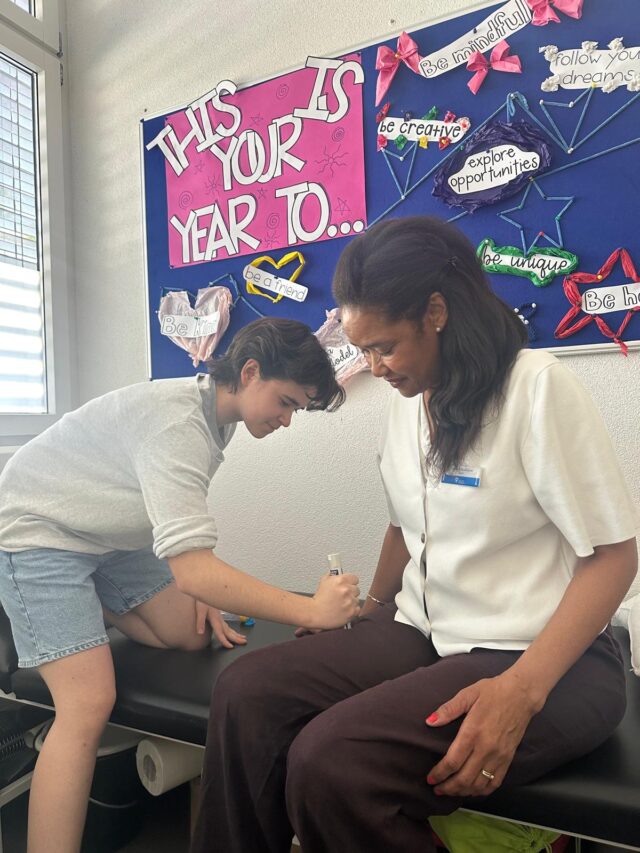 A student applies first aid skills during a supervised practical exercise with support from a staff member.